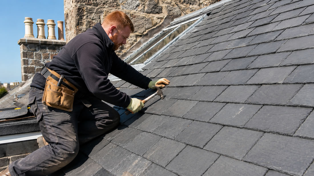 slate roof repairs - roofer on a roof repairing slate